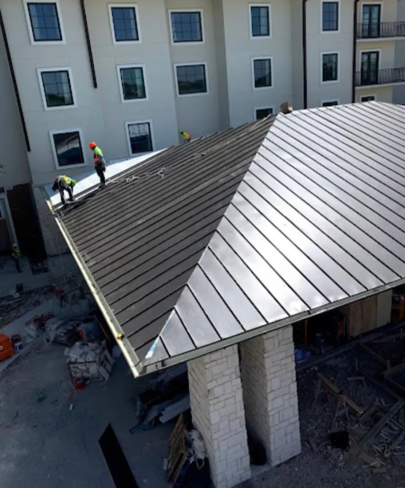 Crew installing standing seam metal roof panels on a commercial project in Cedar Hills
